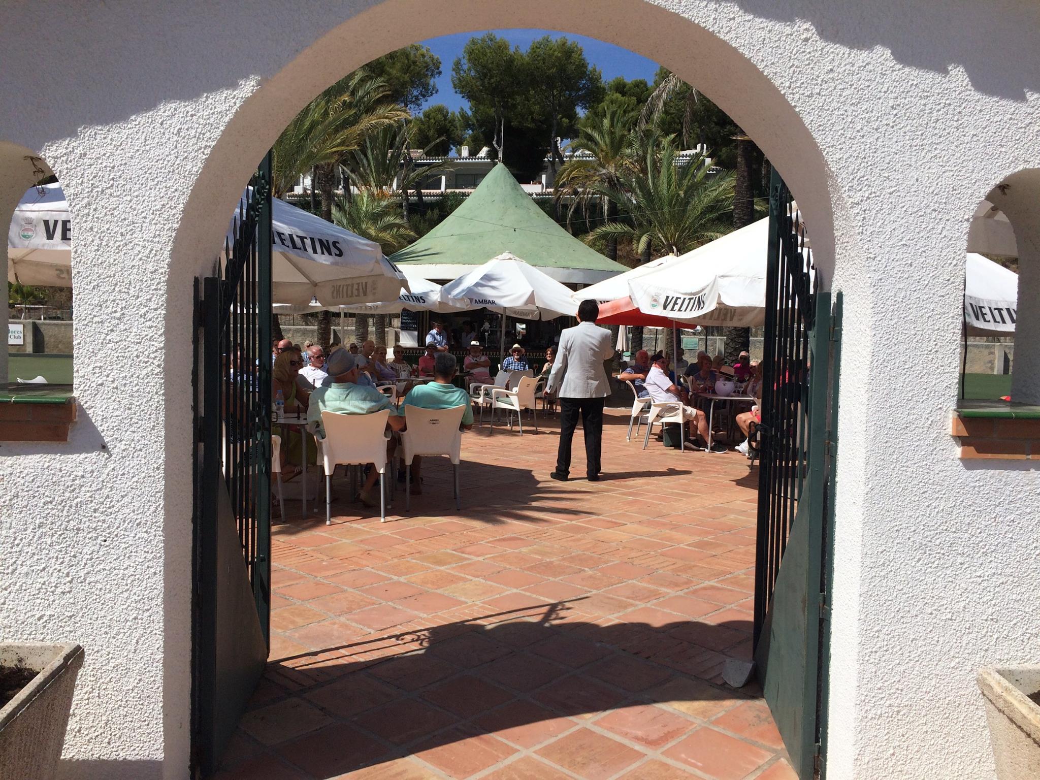 The entrance arch to Miraflores Bowls Club with members on the terrace